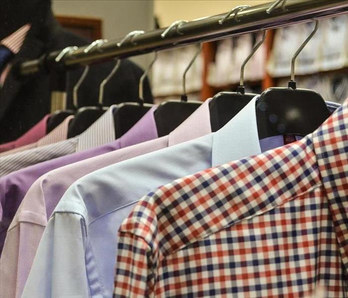 men's dress shirts hanging from hangers in a closet